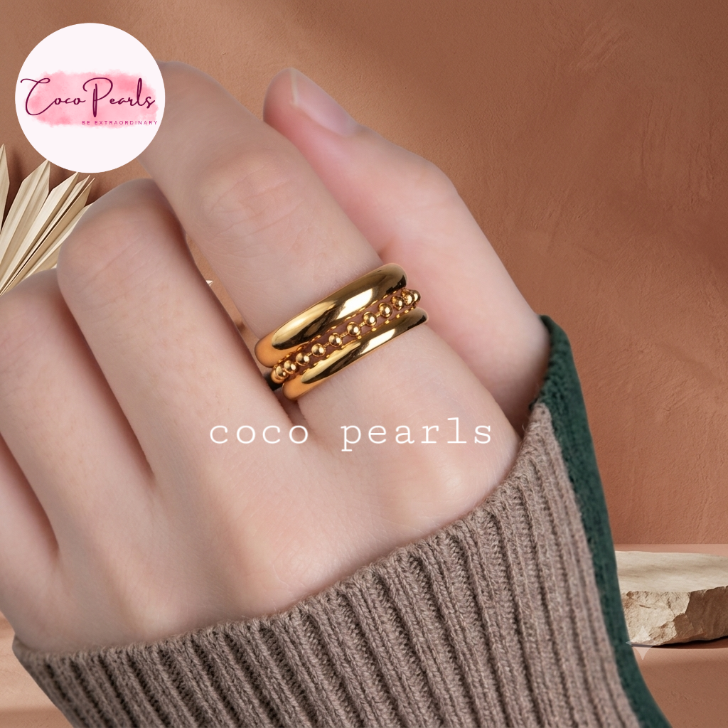 Coco pearls stainless Steel anti tarnish close-up of a hand wearing three layered gold ring, two smooth layer and one with a beaded chain in center.