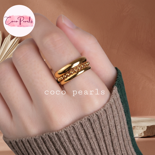 Coco pearls stainless Steel anti tarnish close-up of a hand wearing three layered gold ring, two smooth layer and one with a beaded chain in center.