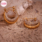 Coco pearls stainless Steel anti tarnish pair of gold crescent hoop earrings adorned with rows of clear rhinestones, displayed on a textured beige stone surface.