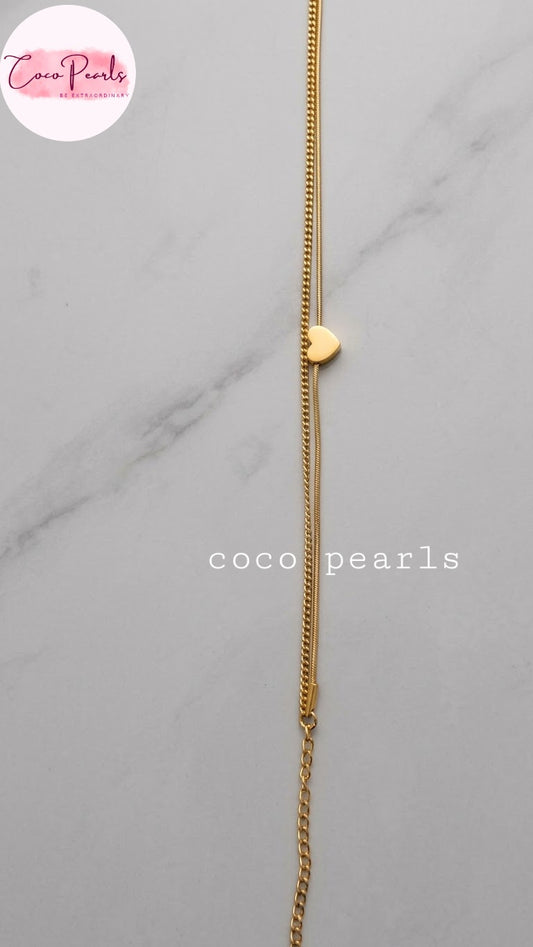 Coco pearls stainless Steel anti tarnish delicate gold chain necklace with a small gold heart charm, displayed vertically on a light gray marble background.