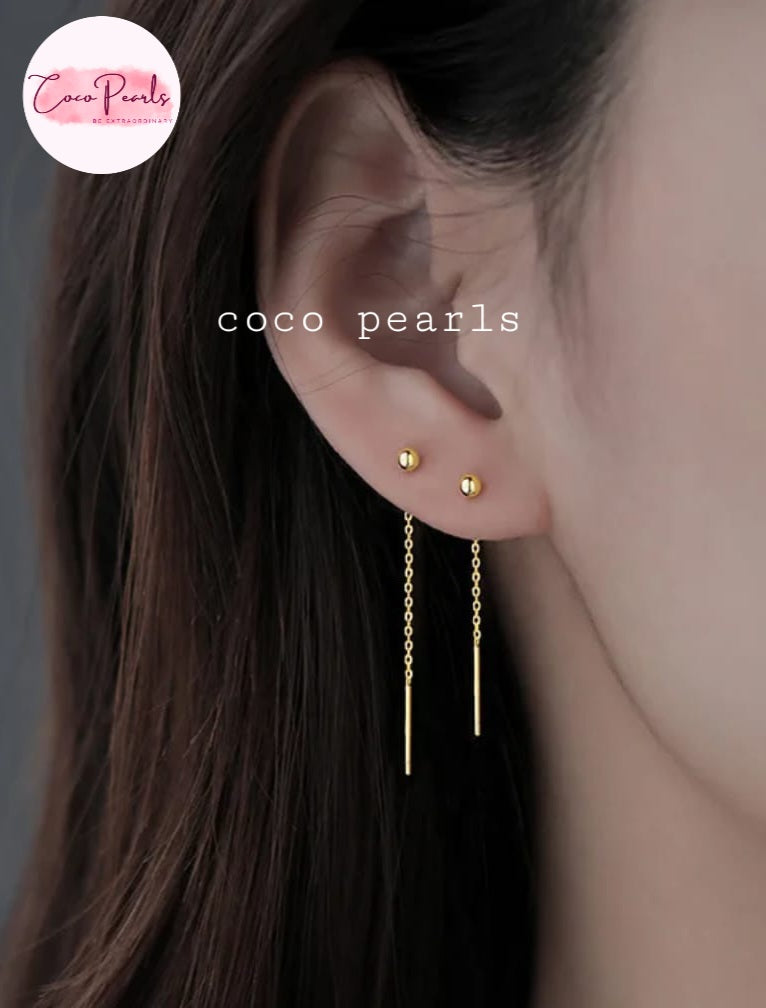 Coco pearls stainless Steel anti tarnish close-up of a model's ear wearing two gold dangle earrings with small round studs and long chain drops.