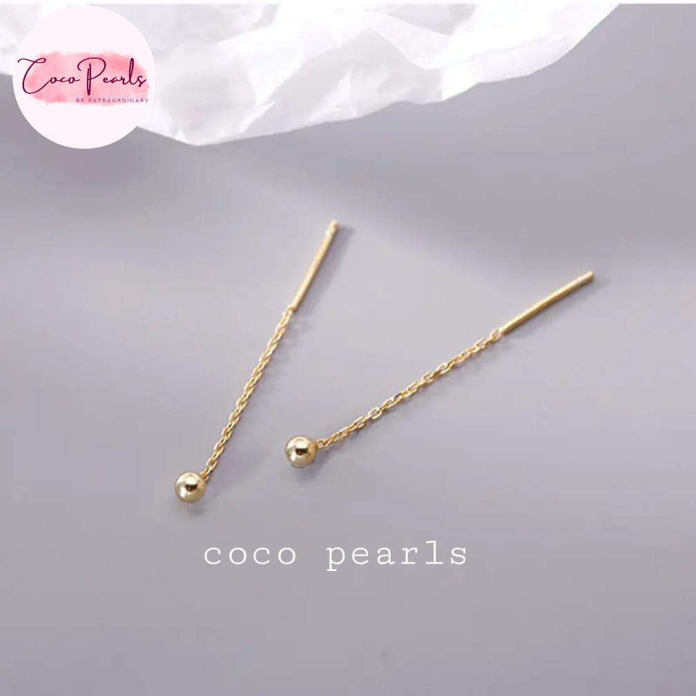 Coco pearls stainless Steel anti tarnish pair of gold-toned drop earrings with a twisted chain and a small polished bead, displayed on a light gray surface