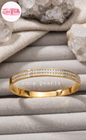 Coco pearls stainless Steel anti tarnish gold bangle bracelet with two rows of pavé-set clear stones, displayed on a gray jewelry tray with crystals and fabric in the background.