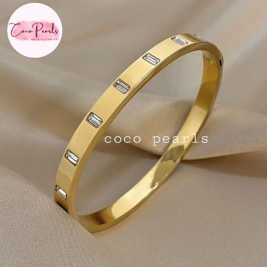Coco pearls stainless Steel anti tarnish gold eternity line handcuff with long diamond studded handcuff displayed on simple background 