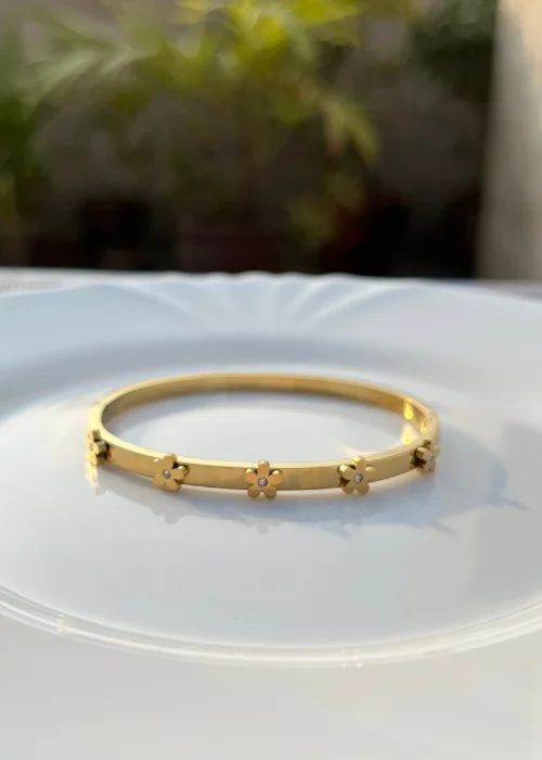 Coco pearls stainless Steel anti tarnish Gold bracelet with floral designs on a white plate