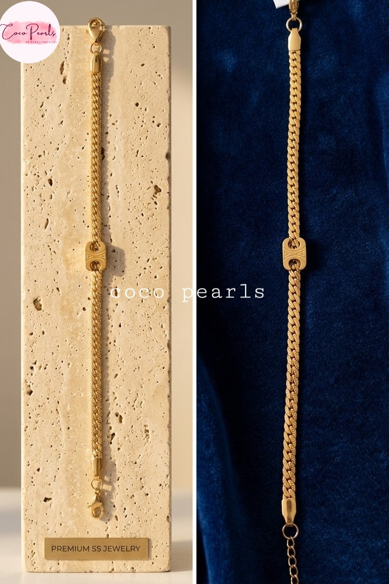 Coco pearls stainless anti tarnish gold chain bracelet with a central square charm and drop chain detail, shown draped over a beige stone display block on the left and over a dark blue velvet surface on the right. 