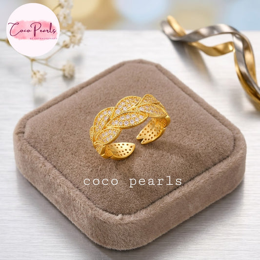 Coco pearls stainless Steel anti tarnish gold leaf-shaped ring with pavé-set clear stones sits on a brown velvet jewelry box.