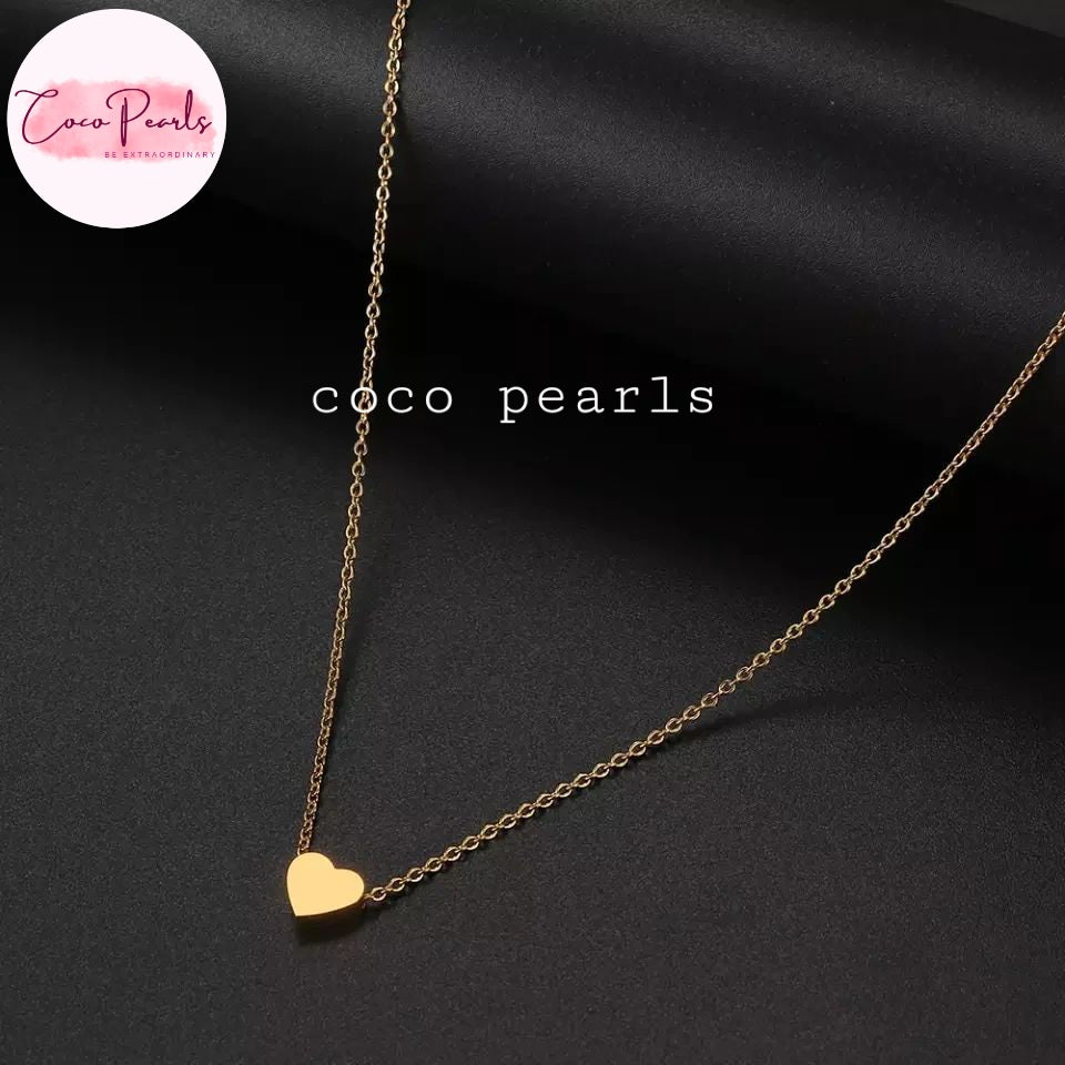 Coco pearls stainless Steel anti tarnish delicate gold chain necklace with a small polished gold heart pendant, displayed on a dark satin fabric background.