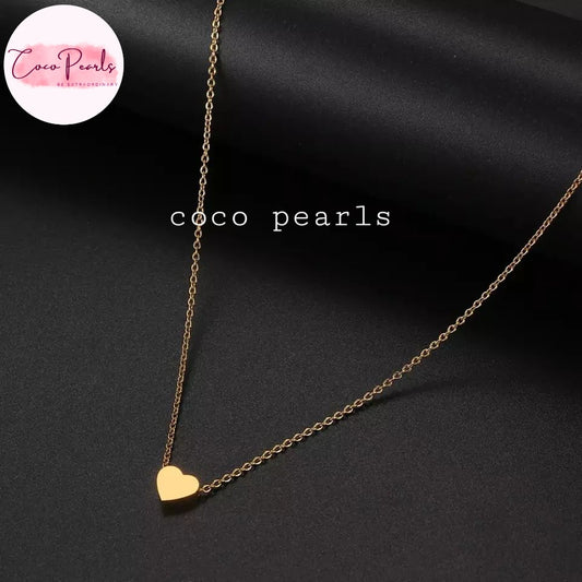 Coco pearls stainless Steel anti tarnish delicate gold chain necklace with a small polished gold heart pendant, displayed on a dark satin fabric background.