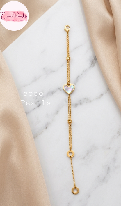 Coco pearls stainless Steel anti tarnish gold heart orbit bracelet with heart charm in center displayed on simple background 