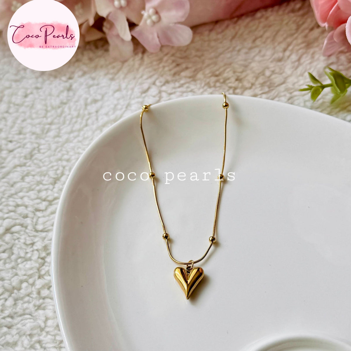 Coco pearls stainless Steel anti tarnish delicate gold chain necklace with a small heart-shaped pendant, displayed on a white plate. The necklace features small gold beads along the chain.