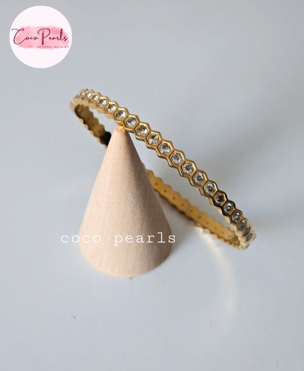 Coco pearls stainless Steel anti tarnish gold eternity-style ring with small clear stones set in a repeating hexagonal pattern, displayed on a beige cone stand against a light gray background.