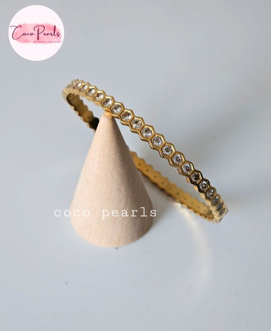 Coco pearls stainless Steel anti tarnish gold eternity-style ring with small clear stones set in a repeating hexagonal pattern, displayed on a beige cone stand against a light gray background.