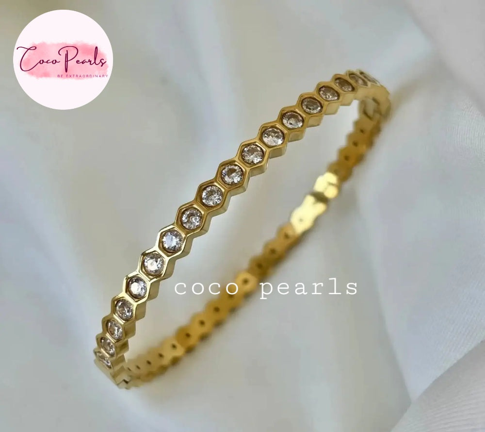 Coco pearls stainless Steel anti tarnish gold bangle bracelet with a continuous row of small clear stones in a hexagonal setting, displayed on a soft white fabric background.