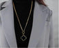 Coco Pearls Stainless Steel Anti Tarnish silver double sided necklace with a one side black one side white clover pendant with long chain mala worn by a person in a gray blazer.