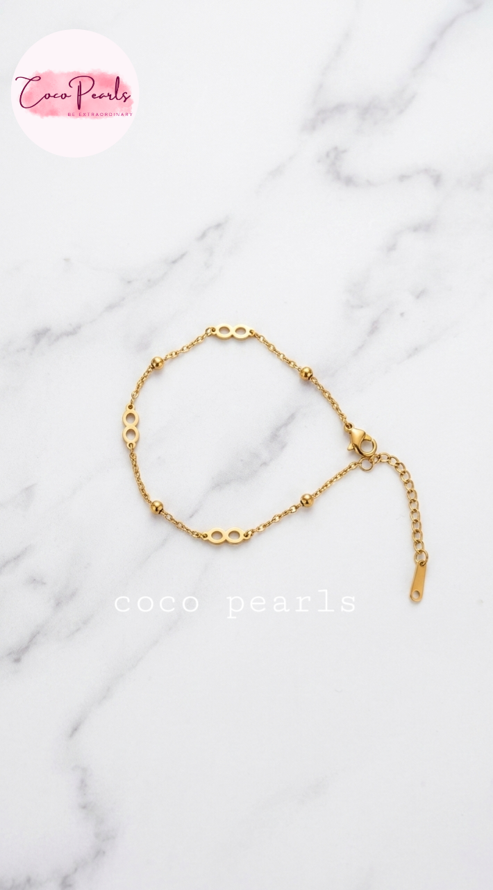 Coco pearls stainless Steel anti tarnish delicate gold chain bracelet with elongated oval links and small bead accents, displayed on a white marble 