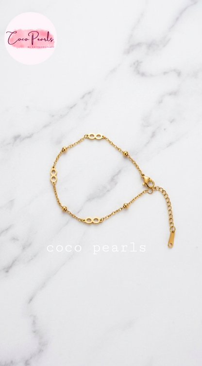 Coco pearls stainless Steel anti tarnish delicate gold chain bracelet with elongated oval links and small bead accents, displayed on a white marble 