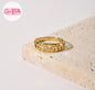 Coco pearls stainless Steel anti tarnish gold ring with an intricate openwork filigree pattern, resting on a textured beige stone slab against a clean white background.