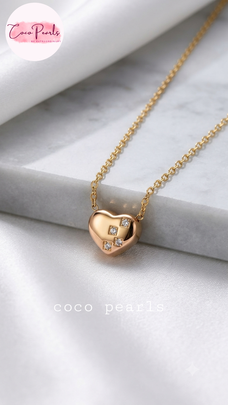 Coco pearls stainless Steel anti tarnish gold heart-shaped pendant necklace with a small diamond-like crystal cluster on the front, displayed on a white marble
