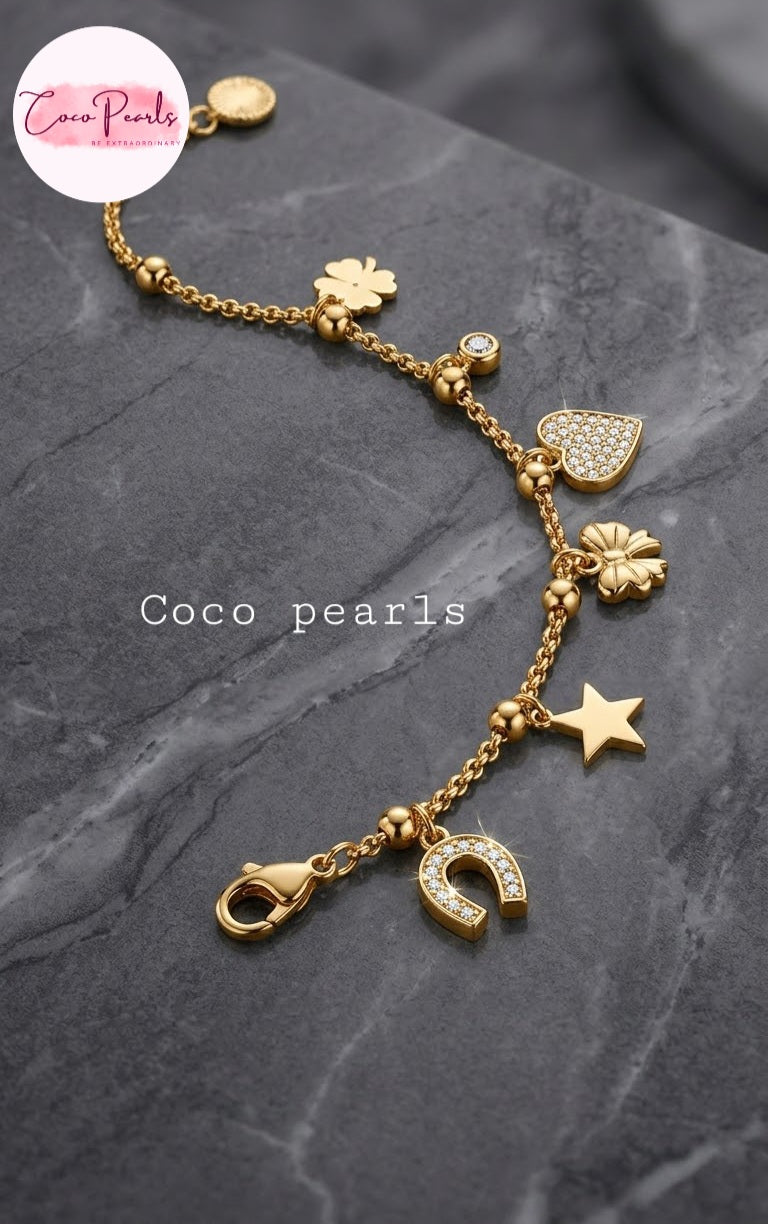 Coco pearls stainless Steel anti tarnish bracelet with various charms including a horseshoe, star, clover, heart, and flower, displayed on a dark gray marble surface.