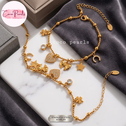 Coco pearls stainless Steel anti tarnish gold-toned multi-charm necklace from Coco Pearls, featuring various star, flower, heart, and crescent moon charms, displayed on a white marble slab and dark gray fabric.