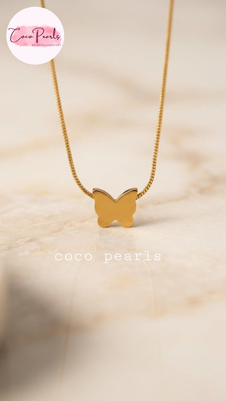 Coco pearls stainless Steel anti tarnish delicate gold chain necklace with a small butterfly-shaped pendant, displayed on a light beige marble surface. 