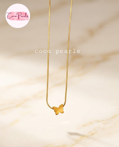 Coco pearls stainless Steel anti tarnish delicate gold chain necklace with a small butterfly pendant, displayed against a light beige marble background.