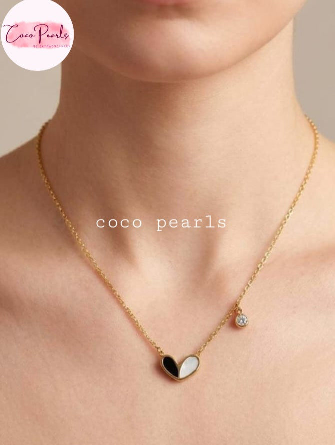 Coco pearls stainless Steel anti tarnish close-up of a model's neck and chest wearing a delicate gold chain necklace. The necklace features a heart-shaped pendant