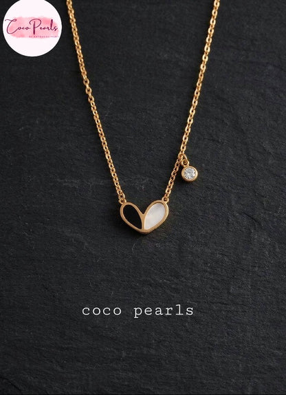 Coco pearls stainless Steel anti tarnish gold chain necklace featuring a heart-shaped pendant with a white pearl inlay and a small round clear stone charm, displayed on a dark textured slate background