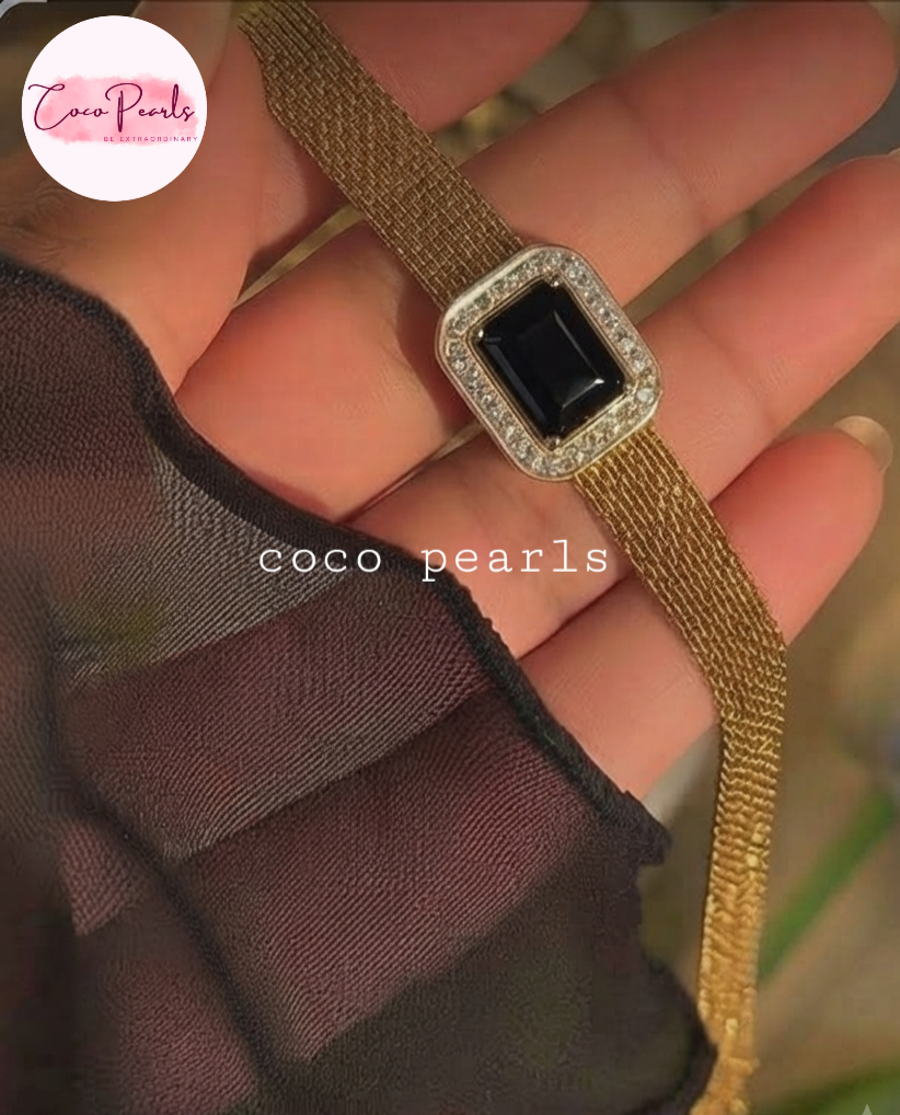 Coco pearls stainless Steel anti tarnish gold mesh bracelet with a rectangular black gemstone and a diamond-encrusted border, held in a hand. 