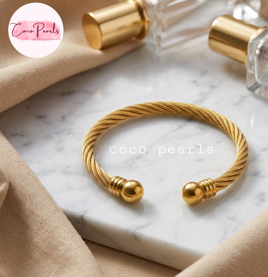 Coco pearls stainless Steel anti tarnish gold orb twist handcuff displyed on simple background 