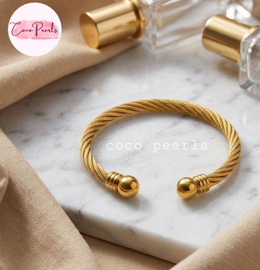 Coco pearls stainless Steel anti tarnish gold orb twist handcuff displyed on simple background 