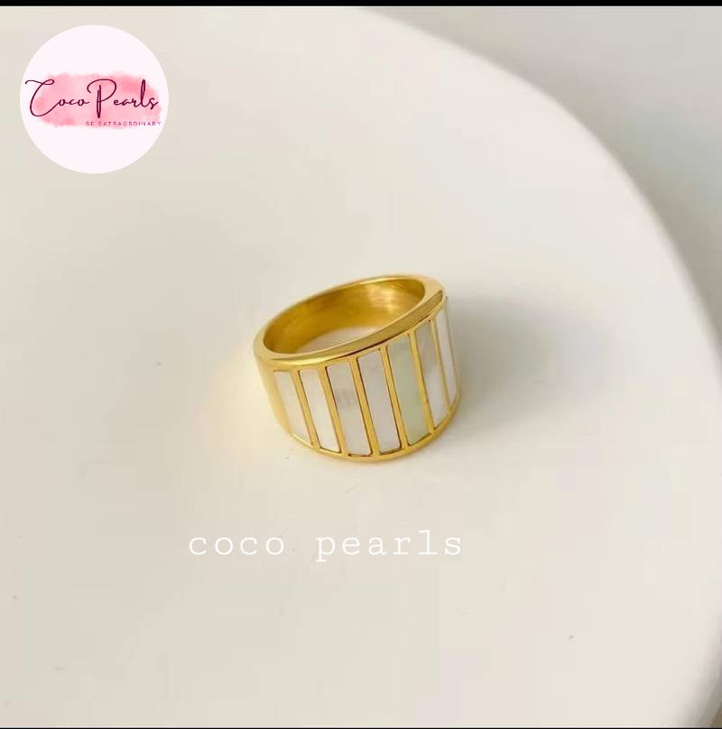 Coco pearls stainless Steel anti gold ring with vertical white pearl inlays, displayed on a white curved surface