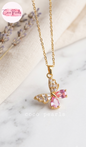 Coco pearls stainless Steel anti tarnish Gold butterfly pendant necklace with pink teardrop crystals and clear rhinestones, displayed on a marble surface with a cream fabric backdrop.