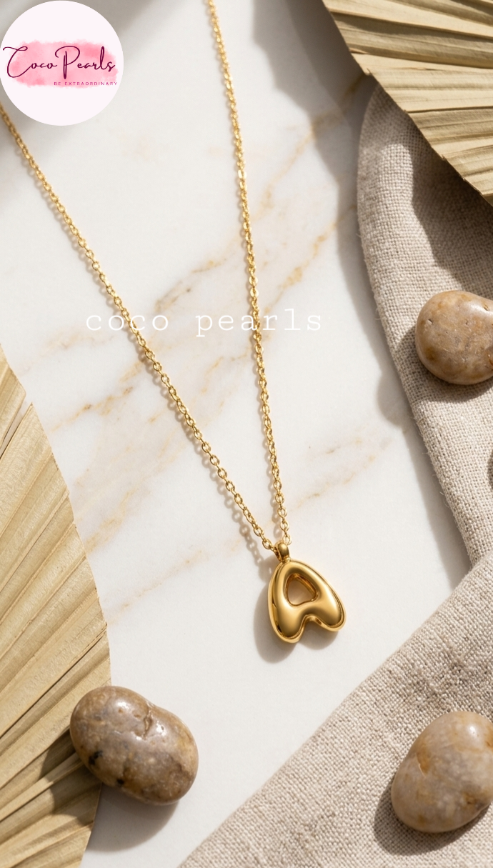 Coco pearls stainless Steel anti tarnish gold A-shaped pendant necklace on a delicate gold chain, styled on a white marble surface