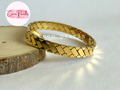 Coco pearls stainless Steel anti tarnish gold regal grid handcuff displayed on simple background 