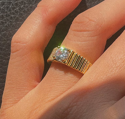 Coco pearls stainless Steel anti tarnish gold gold ring with a round clear gemstone, worn on a finger. 