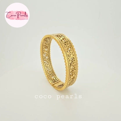 Coco pearls stainless Steel anti tarnish gold bangle bracelet with intricate filigree cutouts and a scalloped edge, displayed on a light gray background 
