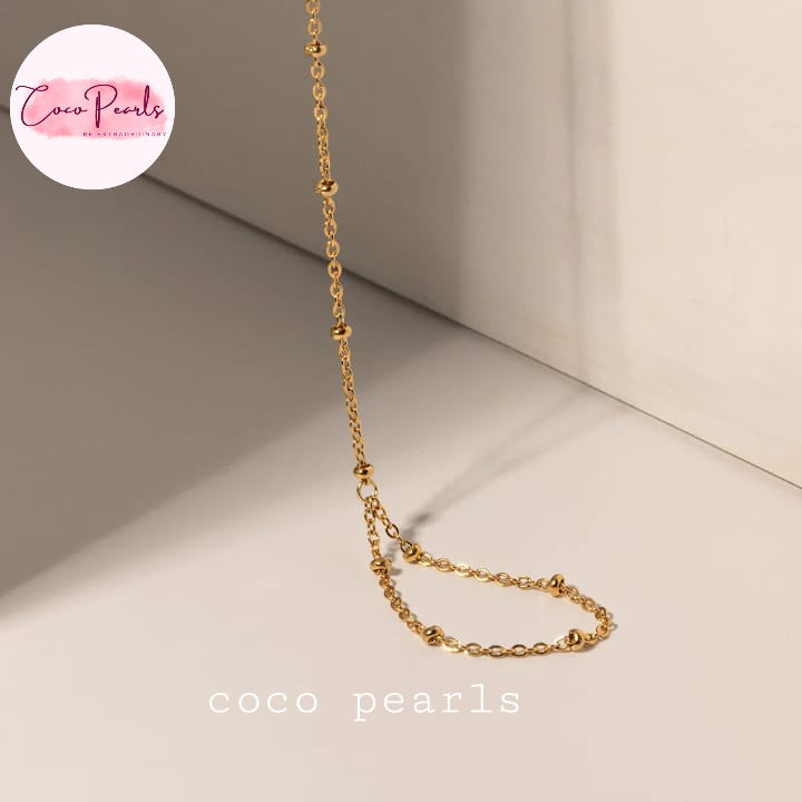 Coco pearls stainless Steel anti tarnish gold small ball chain hand harness displayed on simple background 