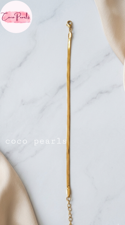 Coco pearls stainless Steel anti tarnish gold  thin snake chain bracelet displayed on simple background 