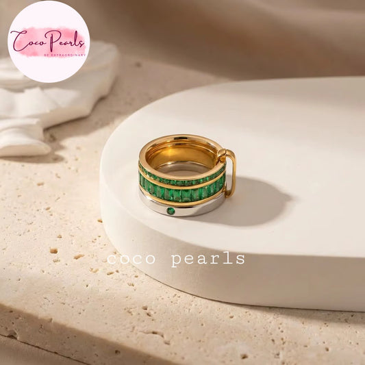 Coco pearls stainless Steel anti tarnish gold and silver ring with a channel of green emerald-cut stones, displayed on a white ceramic dish. 