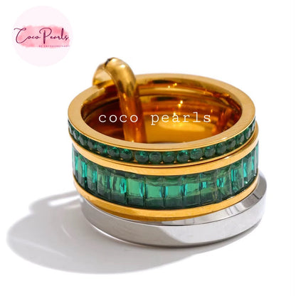 Coco pearls stainless Steel anti tarnish gold-plated stacking ring set featuring a top gold ring with a curved hook, a middle ring set with emerald-cut green crystals, and a bottom silver-toned ring, displayed on simple background 