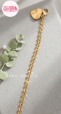 Coco pearls stainless Steel anti tarnish gold chain accessory with a textured sunburst heart charm and lobster clasp, displayed on a gray velvet surface 