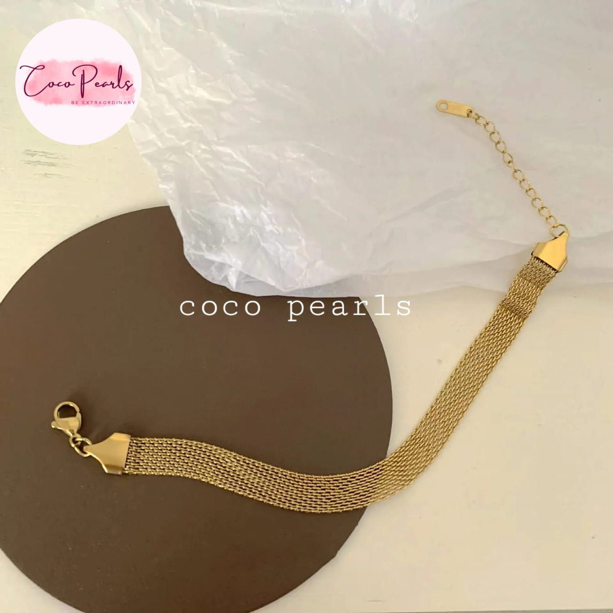 Coco pearls stainless Steel anti tarnish gold mesh bracelet with a lobster clasp and extension chain, displayed on a brown circular prop with a white background