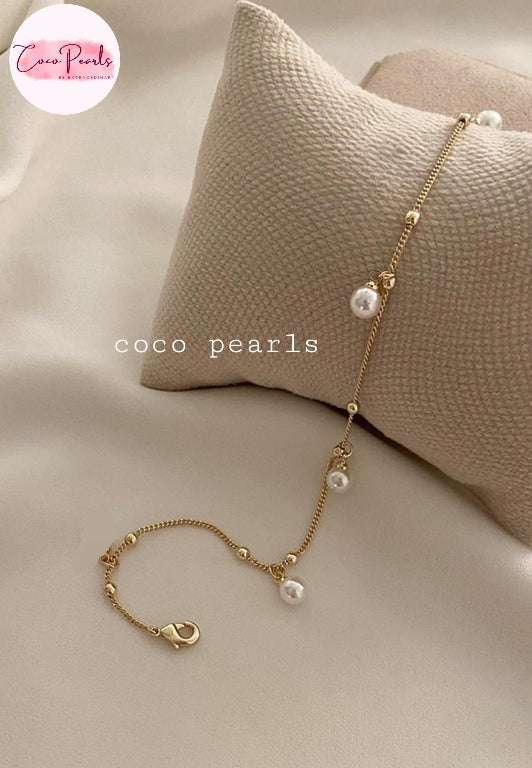 Coco pearls stainless Steel anti tarnish delicate gold chain anklet with three white freshwater pearls, displayed on a textured beige pillow against a soft beige fabric background.