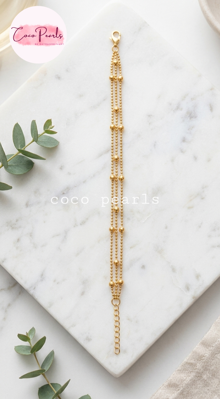 Coco pearls stainless Steel anti tarnish delicate gold chain bracelet with multiple strands of small bead chains and a lobster clasp, displayed on a white marble tray
