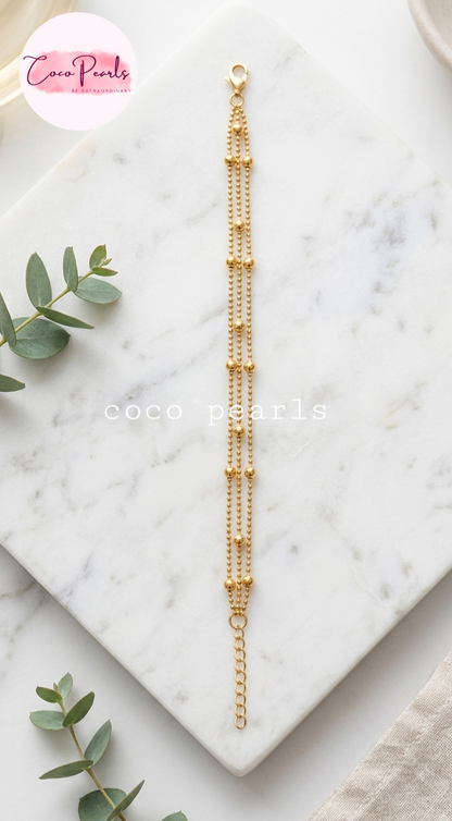 Coco pearls stainless Steel anti tarnish delicate gold chain bracelet with multiple strands of small bead chains and a lobster clasp, displayed on a white marble tray