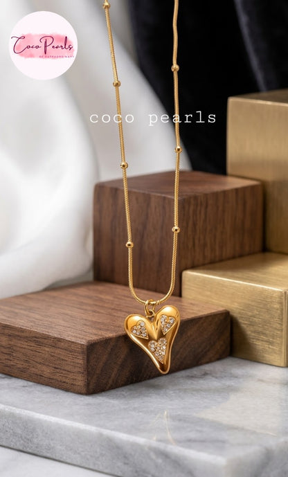 Coco pearls stainless Steel anti tarnish gold heart pendant necklace with small clear stones, displayed on a gold beaded chain.