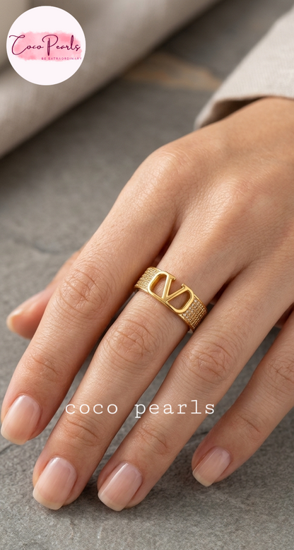 Coco pearls stainless Steel anti tarnish A close-up of a hand wearing a gold ring with a prominent interlocking V logo, representing the Valentino-style Coco Pearls design.