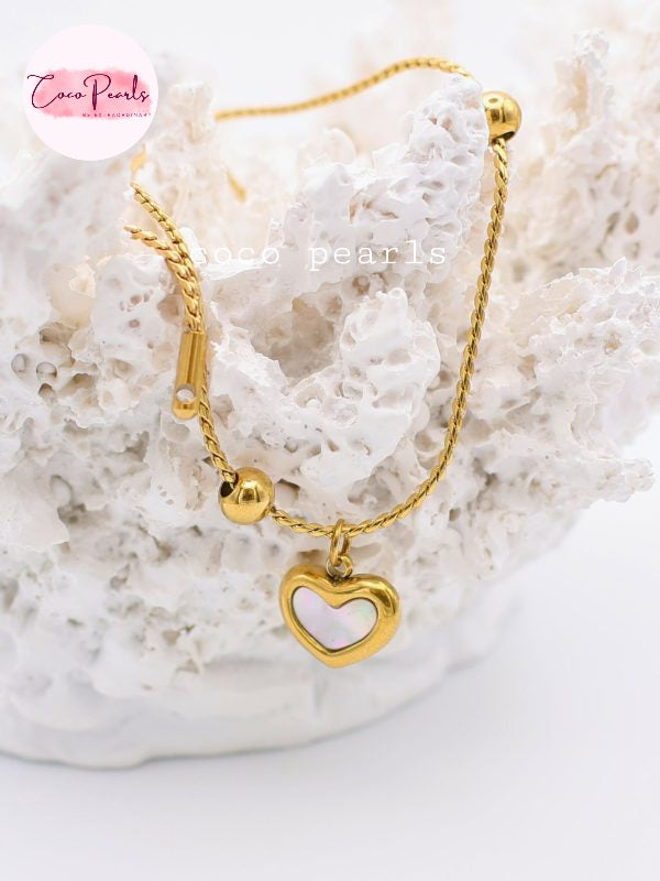 Coco pearls stainless Steel anti tarnish Gold bracelet with a heart-shaped charm on a white stone background,